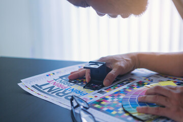 Crop image of worker checking print quality of media graphics proof print in printing industry....