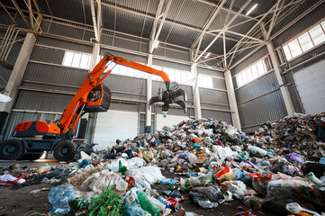 Grabbing excavator collects garbage in plant warehouse - 538781231
