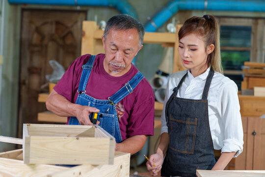 Tutor With Female Carpentry Student In Workshop Studying For Apprenticeship At College ,Teacher explaining a structure students while standing in a woodwork class