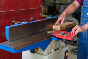 Tutor With Male Carpentry Student In Workshop Studying For Apprenticeship At College Using Bench Saw