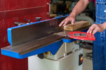 Tutor With Male Carpentry Student In Workshop Studying For Apprenticeship At College Using Bench Saw