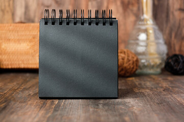 mockup square black spiral notebook on wood table and decor with wicker decoration countryside items