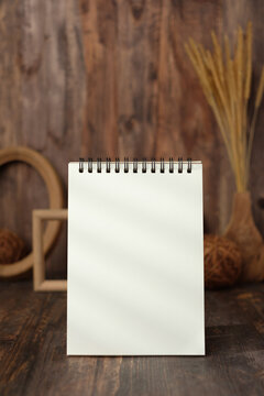 mockup blank spiral notebook with wood photo frame and wicker ball on table