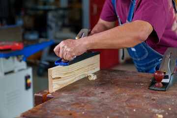 carpenter working with plane on wooden background