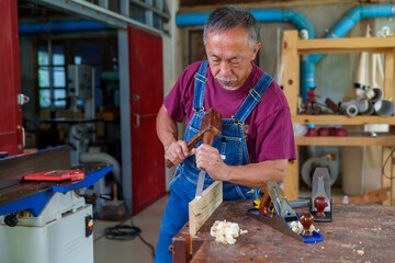 carpenter hands working with a chisel and hammer on wooden workbench