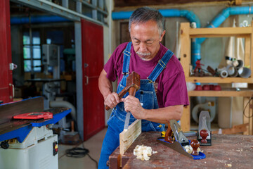 carpenter hands working with a chisel and hammer on wooden workbench
