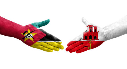 Handshake between Gibraltar and Mozambique flags painted on hands, isolated transparent image.