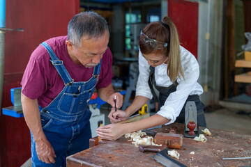 Tutor With Female Carpentry Student In Workshop Studying For Apprenticeship At College ,Teacher explaining a structure students while standing in a woodwork class