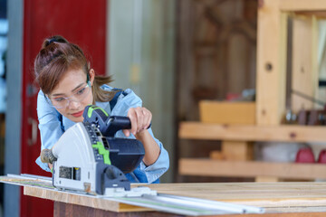 Female Carpentry Student In Workshop Studying For Apprenticeship At College Using Bench Saw