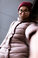 Portrait of a woman in a down jacket and hat in winter in the city of Yalta. Vertical photo.