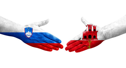 Handshake between Gibraltar and Slovenia flags painted on hands, isolated transparent image.