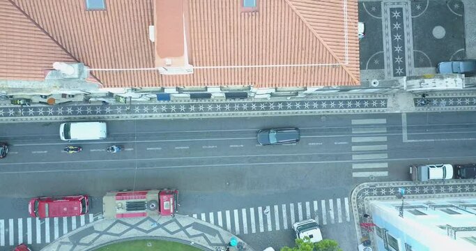 Aerial top down drone shot over traffic in rua do alecrim, surrounded by the city of Lisbon, Portugal, on a sunny evening. Portuguese coblestone history.