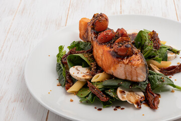 Portion of salmon with cherry tomato on top and vegetables