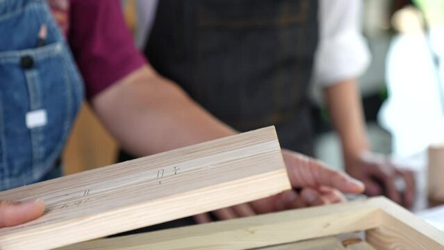 Tutor With Female Carpentry Student In Workshop Studying For Apprenticeship At College ,Teacher explaining a structure students while standing in a woodwork class