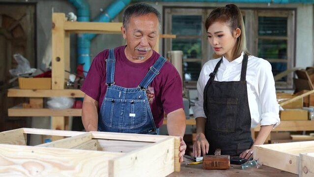 Tutor With Female Carpentry Student In Workshop Studying For Apprenticeship At College ,Teacher explaining a structure students while standing in a woodwork class
