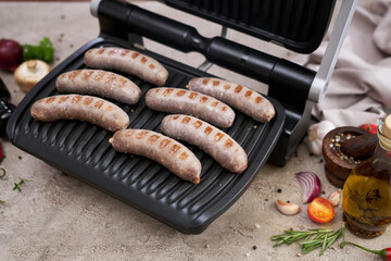 Grilled sausages on electric grill at domestic kitchen