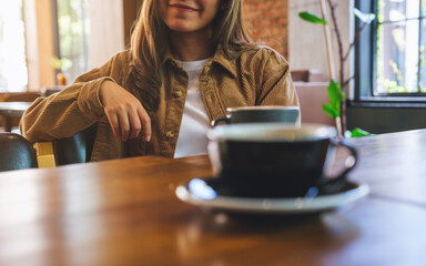 Closeup image of a young woman drinking coffee with friend in cafe