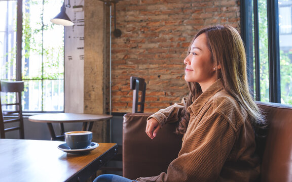 Portrait image of a beautiful young asian woman with coffee cup on wooden table in cafe