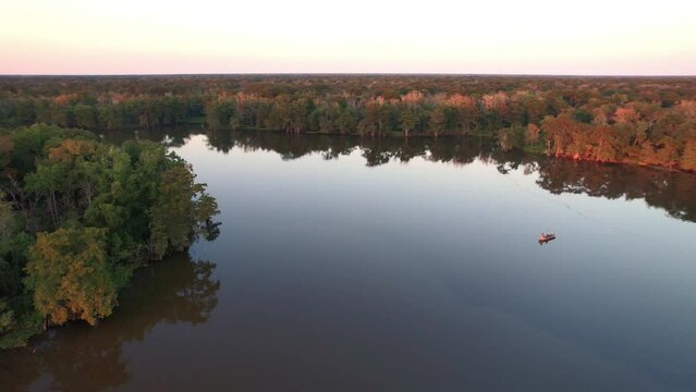 Louisiana swamp bay bayou cypress trees guy in boat fishing golden hour sunset