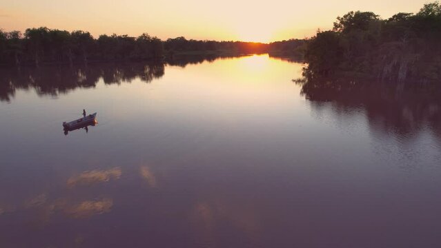 Louisiana swamp bay bayou cypress trees guy in boat fishing golden hour sunset steady shot