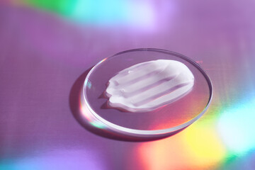 Smear of cream in petri dish on holographic background with iridescent highlights