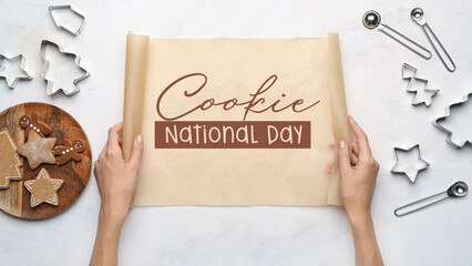 Female hands with baking paper and different cookie cutters on light background. National Cookie Day