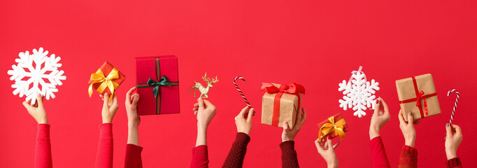 Many hands with Christmas gifts and decor on red background