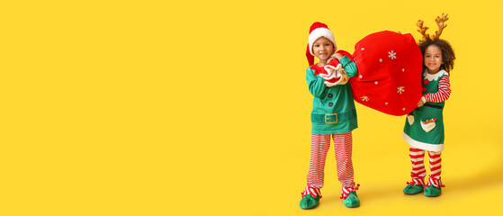 Cute little elves holding Santa bag on yellow background with space for text - obrazy, fototapety, plakaty