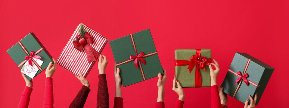 Many hands with Christmas gifts on red background