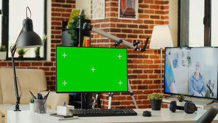 Empty office desk with greenscreen template on monitor, isolated mockup background running on computer. Desktop pc with blank copy space on chroma key display, mock up green screen.