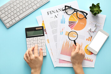 Female hands with business charts, gadgets and stationery on blue background