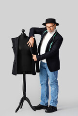 Mature fashion designer with mannequin on grey background