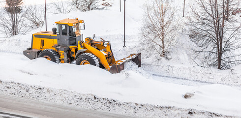 Snow clearing. Tractor clears the way after heavy snowfall. A large orange tractor removes snow...