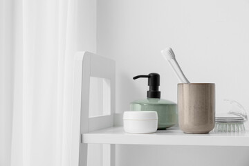 Bath accessories on shelf near white wall, closeup