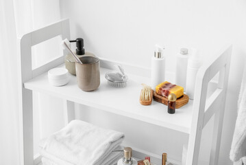 Bath accessories on shelf unit near white wall