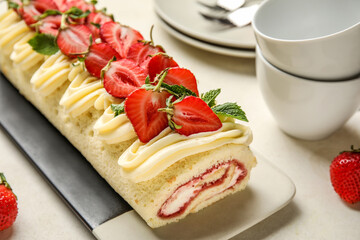 Plate of tasty roll cake with fresh strawberry on light background, closeup