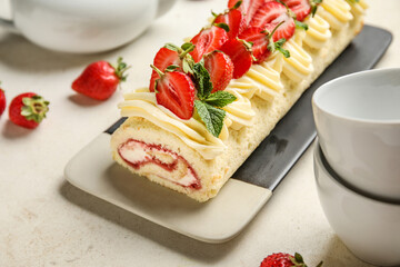 Plate of tasty roll cake with fresh strawberry on light background