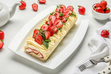 Plate of delicious roll cake with fresh strawberry on light background