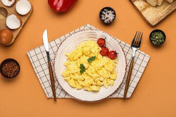 Plate of tasty scrambled eggs, tomatoes and spices on color background