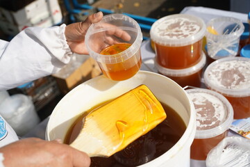 The seller pours fresh honey into a container at the market.