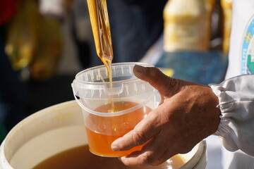 The seller pours fresh honey into a container at the market.