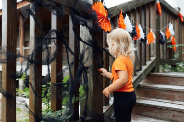 Obraz na płótnie Canvas Lifestyle portrait of Happy caucasian baby girl with blonde hair in black orange costume celebrating Halloween outdoor