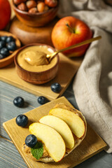 Tasty sandwich with nut butter and apples on grey wooden table, closeup