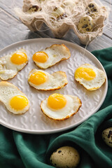 Plate with fried quail eggs on table, closeup