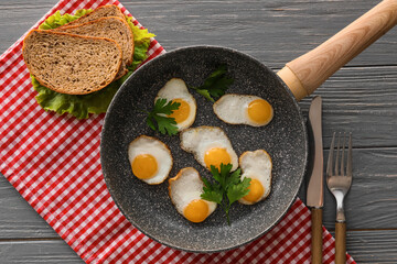 Frying pan of tasty fried quail eggs on dark wooden background