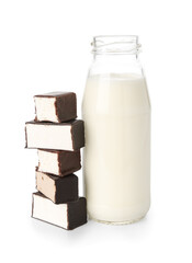 Bottle of milk and tasty candies on white background