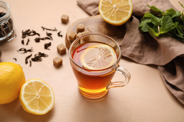 Glass cup of black tea with lemon on beige background, closeup