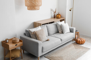 Interior of modern living room with grey sofa and pumpkins