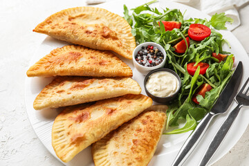 Plate with tasty chebureks and salad on light background, closeup