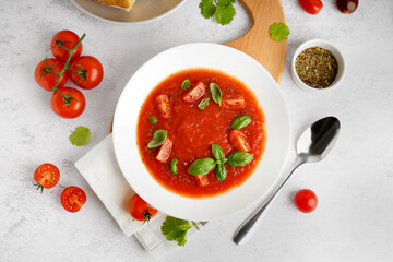 Plate with delicious tomato soup and spices on light background